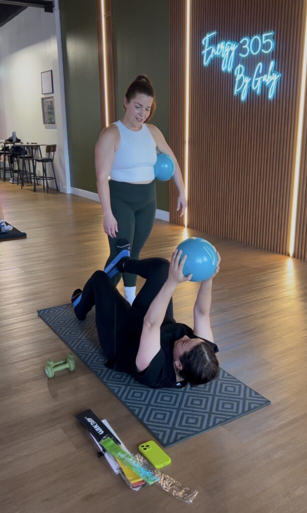 Gwen coaching a core exercise with a weighted ball at Sculpt and Core, Energy 305 by Gaby, West Kendall